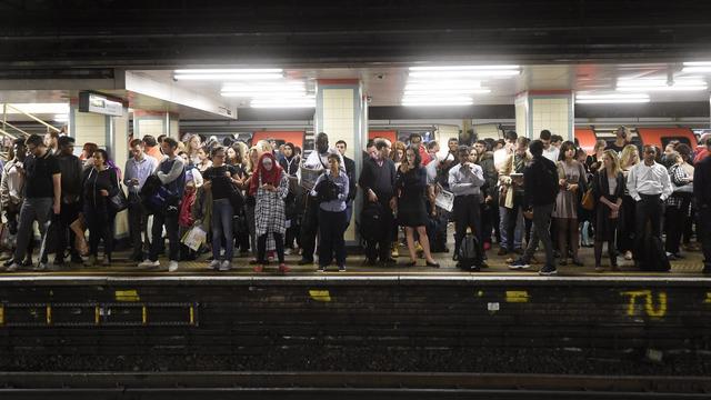 Des pendulaires attendent sur un quai du métro londonien. [Keystone - Facundo Arrizabalaga]