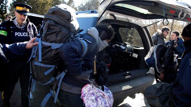 Une famille de quatre personnes prise en charge par la police canadienne à la frontière près de Hemmingford, au Québec. [AFP - Christinne Muschi]