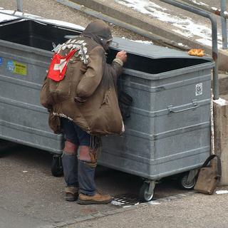 Un sans-abri fouille dans les poubelles d'un centre commercial à Neuchâtel. [Keystone - Sandro Campardo]