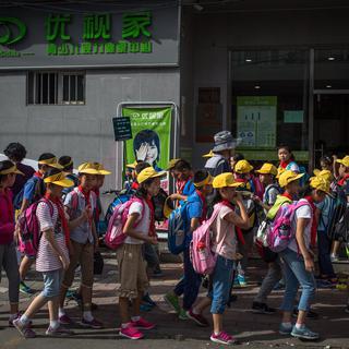 Des écoliers chinois rentrent chez eux à la fin des classes. [Keystone - Roman Pilipey/ EPA]