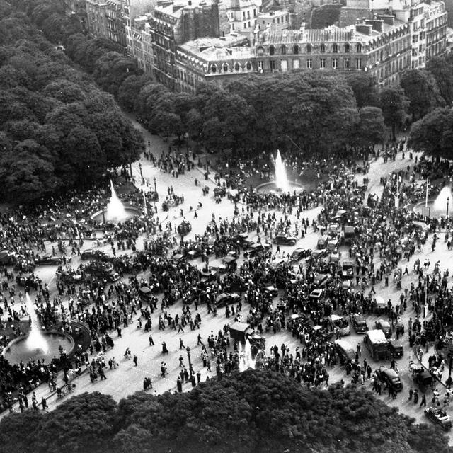 Des foules heureuses se rassemblent autour du Rond-Point sur les Champs-Elysées, à Paris, le 8 mai 1945, pour célébrer l'annonce de la capitulation inconditionnelle de l'Allemagne [Keystone - Henry L. Griffin]