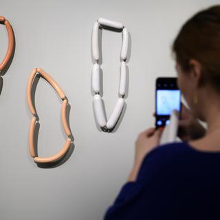 Une femme observe des colliers en forme de saucisse dans le cadre de l'exposition Carte blanche à David Bielander, au mudac, à Lausanne. [Keystone - Laurent Gillieron]