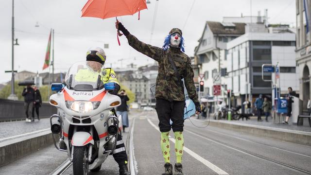 Un manifestant protège de la pluie un policier dans les rues de Zurich, ce 1er Mai 2017. [ENNIO LEANZA]