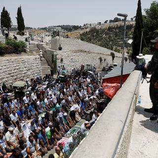 Des policiers israéliens observent des Palestiniens en train de prier dans la vieille-ville de Jérusalem. [Reuters - Ronen Zvulun]