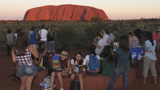 Des touristes admirent le coucher de soleil sur Uluru en 2014. [AP/Keystone - Rob Griffith]