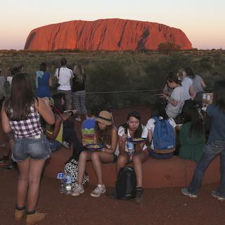 Des touristes admirent le coucher de soleil sur Uluru en 2014. [AP/Keystone - Rob Griffith]