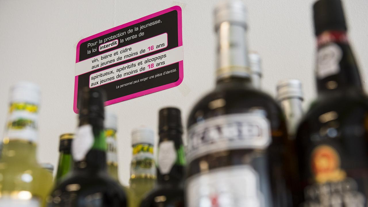 Un rayon d'alcool avec un panneau interdisant la consommation aux jeunes. [Keystone - Jean-Christophe Bott]