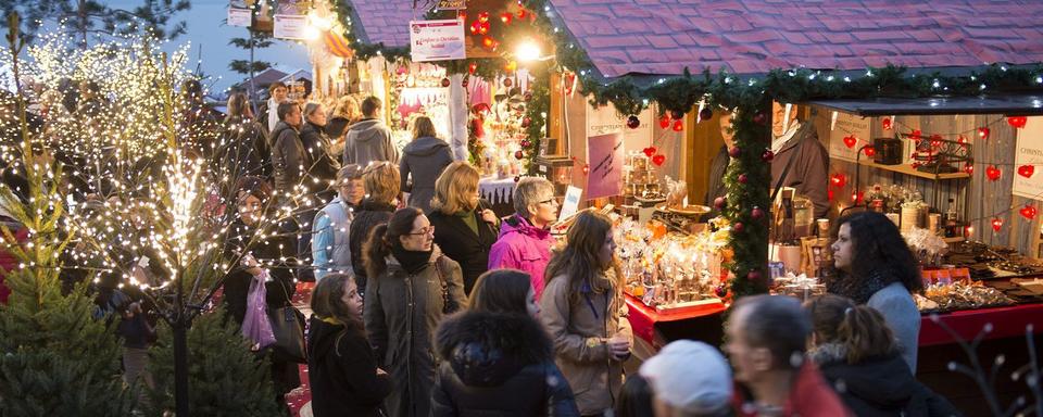 Des personnes se promènent entre les stands du marché de Noël de Montreux. [Keystone - Jean-Christophe Bott]