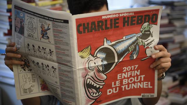 A journalist reads on January 3, 2017 in Paris a special issue of French satirical newspaper Charlie Hebdo to be released in newstands on January 4, almost two years after the January 7, 2015 attack on the offices of the weekly which left 11 dead. 
Eric Feferberg / AFP [AFP - Eric Feferberg]