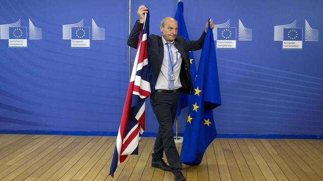 Un membre du protocole avec les drapeaux britannique et européen en juin 2017 à Bruxelles. [AP Photo/Virginia Mayo]