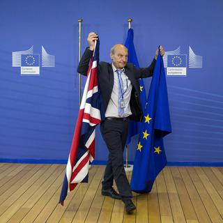 Un membre du protocole avec les drapeaux britannique et européen en juin 2017 à Bruxelles. [AP Photo/Virginia Mayo]