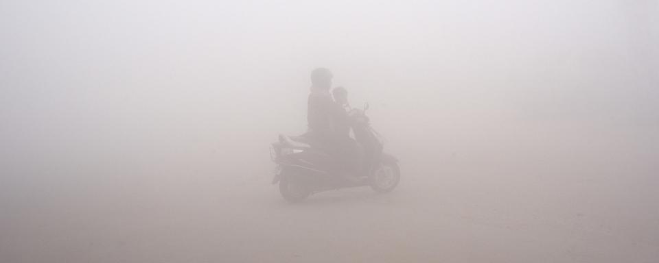 Un scooter dans le smog de New Delhi. [Keystone - AP Photo/R S Iyer]