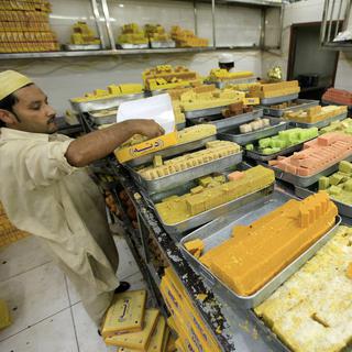 Un vendeur pakistanais dispose à la vente les traditionnelles douceurs de la célébration de l'Aïd el-Fitr, le 24 juin à Peshawar. [keystone - EPA/Arshad Arbab]