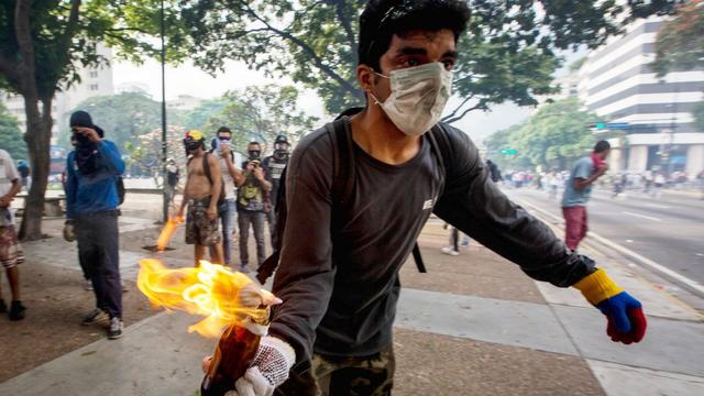 Un manifestant s'apprête à lancer un cocktail Molotov à Caracas. [Keystone - EPA/MIGUEL GUTIERREZ]