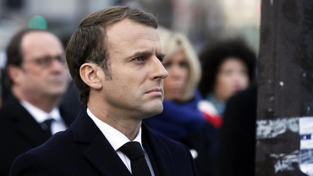 Emmanuel Macron rend hommage aux victimes des attentats. On distingue derrière lui, les silhouettes de son épouse Brigitte et de l'ancien président François Hollande. [EPA/ETIENNE LAURENT / POOL MAXPPP OUT]