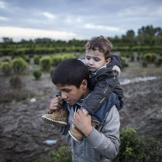 Un migrant porte son frère sur ses épaules, en Hongrie. [AFP - Arpad Kurucz]