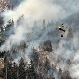 Un hélicoptère en intervention au-dessus d'un feu de forêt à Mesocco, dans le canton des Grisons, fin décembre 2016. [Gabriele Putzu]
