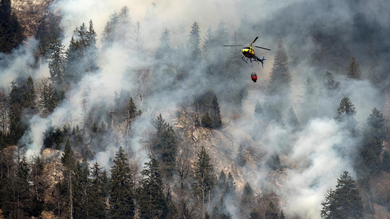 Un hélicoptère en intervention au-dessus d'un feu de forêt à Mesocco, dans le canton des Grisons, fin décembre 2016. [Gabriele Putzu]
