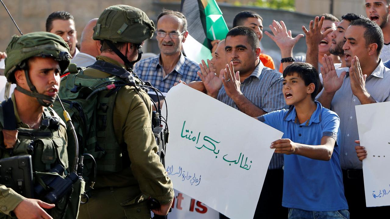 Un jeune Palestinien brandit une pancarte "nous exigeons notre dignité". [Reuters - Mussa Qawasma]