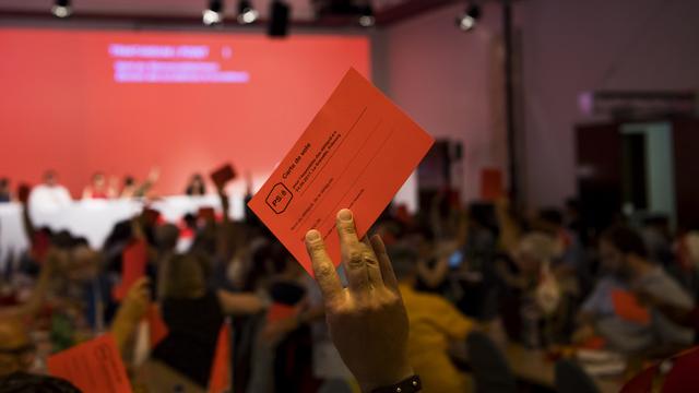 Un délégué socialiste lève sa carte de vote lors de l'assemblée du PS à Fribourg. [Keystone - Jean-Christophe Bott]