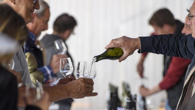 Des personnes dégustent du vin lors des caves ouvertes à Dardagny, près de Genève. [Keystone - Martial Trezzini]