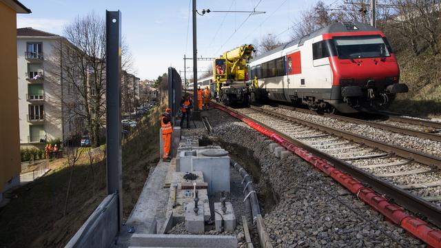 Des ouvriers travaillent le jeudi 23 février pour réparer les dégâts survenus après un glissement de terrain le long des voies CFF à Lausanne. [Keystone - Jean-Christophe Bott]