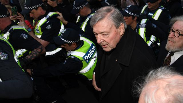 La cardinal Georges Pell lors de son arrivée mercredi, entouré de policiers,  au tribunal de Melbourne pour sa première audition devant la justice australienne. [Keystone - TRACEY NEARMY]