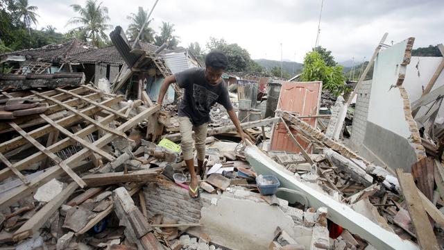 Un homme marche parmi les débris causés par le séisme dans l'ouest de l'île indonésienne de Lombok. [AP Photo - Firdia Linsawati]