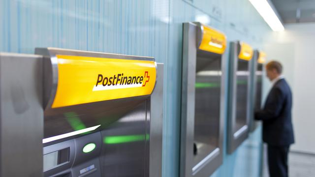 Client de Postfinance à un distributeur d'argent de la filiale de La Poste. [Keystone]