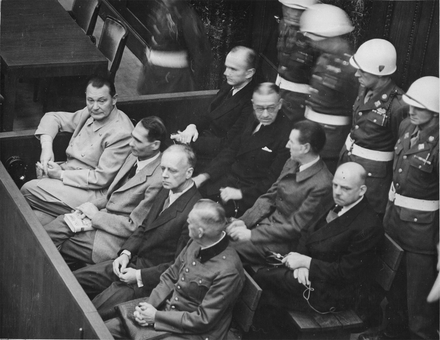 Procès de Nuremberg (1945-1946), les accusés dans leur box. Au premier rang, de gauche à droite: Hermann Göring, Rudolf Heß, Joachim von Ribbentrop, Wilhelm Keitel. Second rang: Karl Dönitz, Erich Raeder, Baldur von Schirach, Fritz Sauckel.  (National Archives and Records Administration)