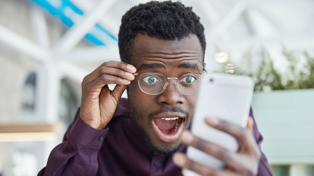 Une jeune homme regarde son Smartphone d'un air choqué. [Fotolia - Wayhome Studio]