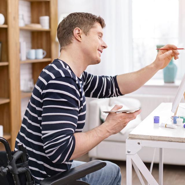 Un homme en fauteuil roulant peint une toile. [Fotolia - Viacheslav Iakobchuk]