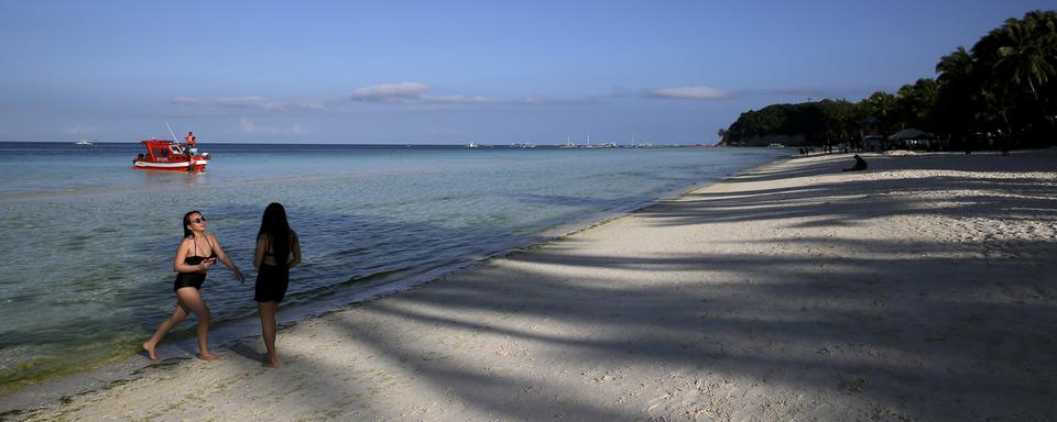 Des touristes sur une plage quasi déserte de l'île de Boraçay, aux Philippines. [AP/Keystone - Aaron Favila]