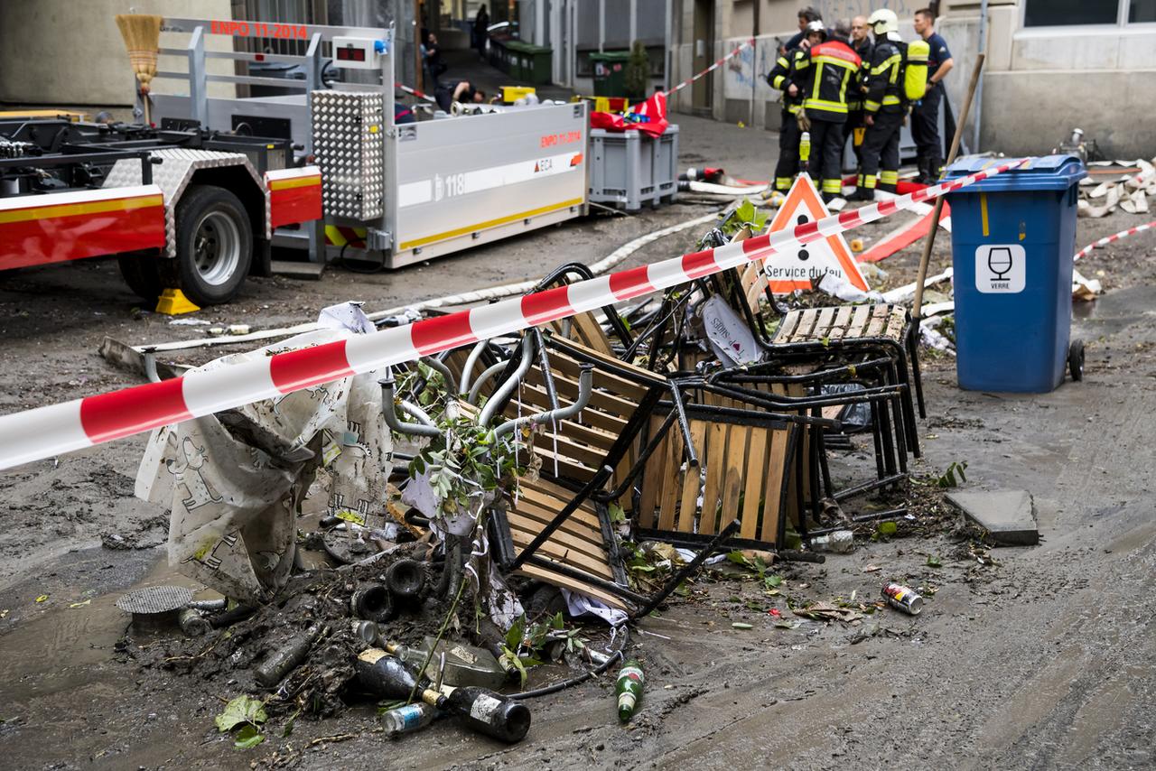 Des pompiers nettoient les dégâts à la rue du Petit-Saint-Jean après les fortes pluies à Lausanne. [keystone - Jean-Christophe Bott]