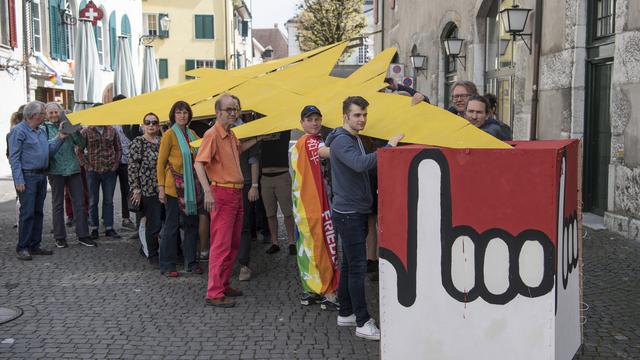 Le Groupe pour une Suisse sans armée (GSsA) jette un avion en papier dans une urne, ce dimanche 15 avril à Soleure. [keystone - Peter Schneider]