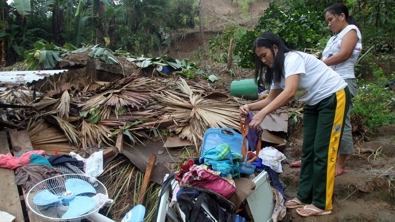 Des habitantes des Philippines tentent de sauver des affaires parmi les décombres de leur habitation, détruite par la tempête tropicale. [EPA/Keystone - Romedor Gloriane]