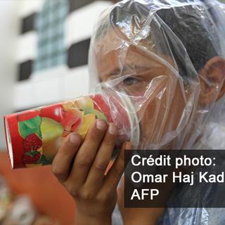 Un enfant syrien teste un masque à gaz de fortune, à Maar Chourin, dans la province d'Idleb (Syrie) le 11 septembre 2018. [AFP - Omar Haj Kadour]