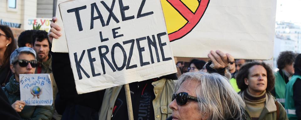 Une femme réclame une taxe sur le kérosène lors d'une manifestation à Marseille. [AFP - Boris Horvat]