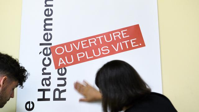 Des personnes placent une affiche lors de la conférence de presse de la ville de Lausanne sur le lancement de la campagne contre le harcèlement de rue, le 30 avril 2018. [Keystone - Laurent Gillieron]