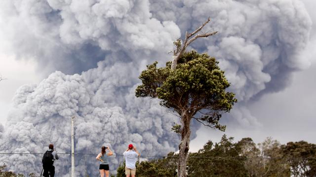 Des passants regardent l'énorme panache de fumée qui s'échappe du volcan Kilauea à Hawaii. [Reuters - Terray Sylvester]