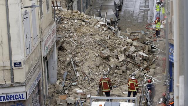 Les secours recherchent des personnes ensevelies dans les décombres de l'immeuble à Marseille. [Keystone - AP Photo/Claude Paris]