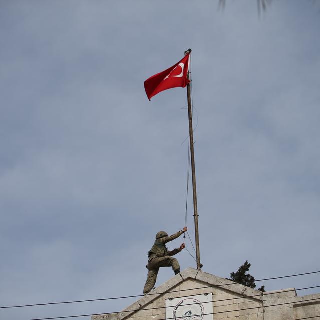 Un soldat hissant le drapeau turc dans le centre-ville d'Afrine, le 18 mars 2018. [Anadolu Agency/AFP - Halil Fidan]