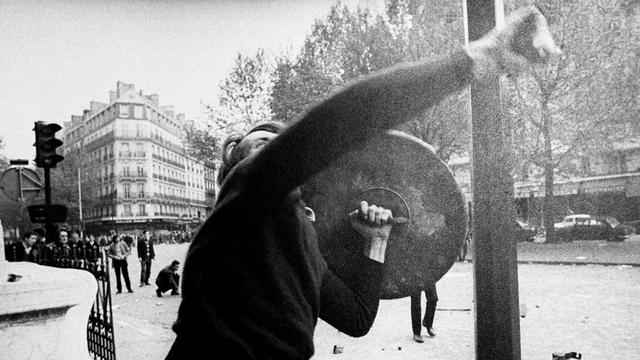 Manifestant lançant un pavé en direction de policiers en mai 1968. [AP/Keystone]
