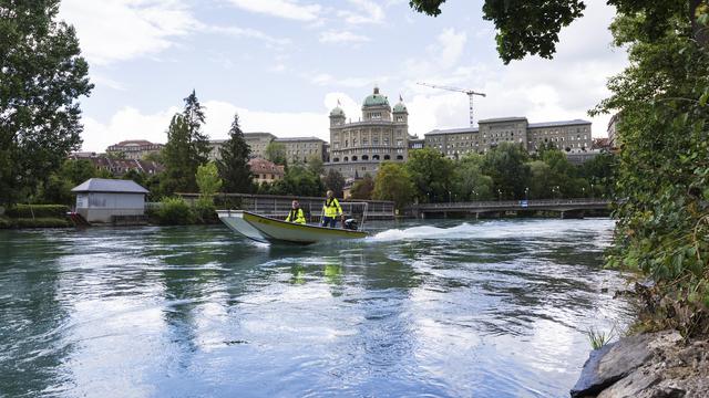 Un bateau navigue sur l'Aar à Berne avec le Palais fédéral en toile de fond en août 2018. [Keystone - Christian Beutler]