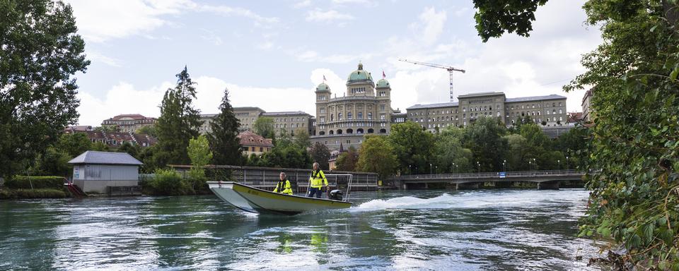 Un bateau navigue sur l'Aar à Berne avec le Palais fédéral en toile de fond en août 2018. [Keystone - Christian Beutler]