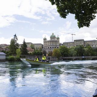 Un bateau navigue sur l'Aar à Berne avec le Palais fédéral en toile de fond en août 2018. [Keystone - Christian Beutler]