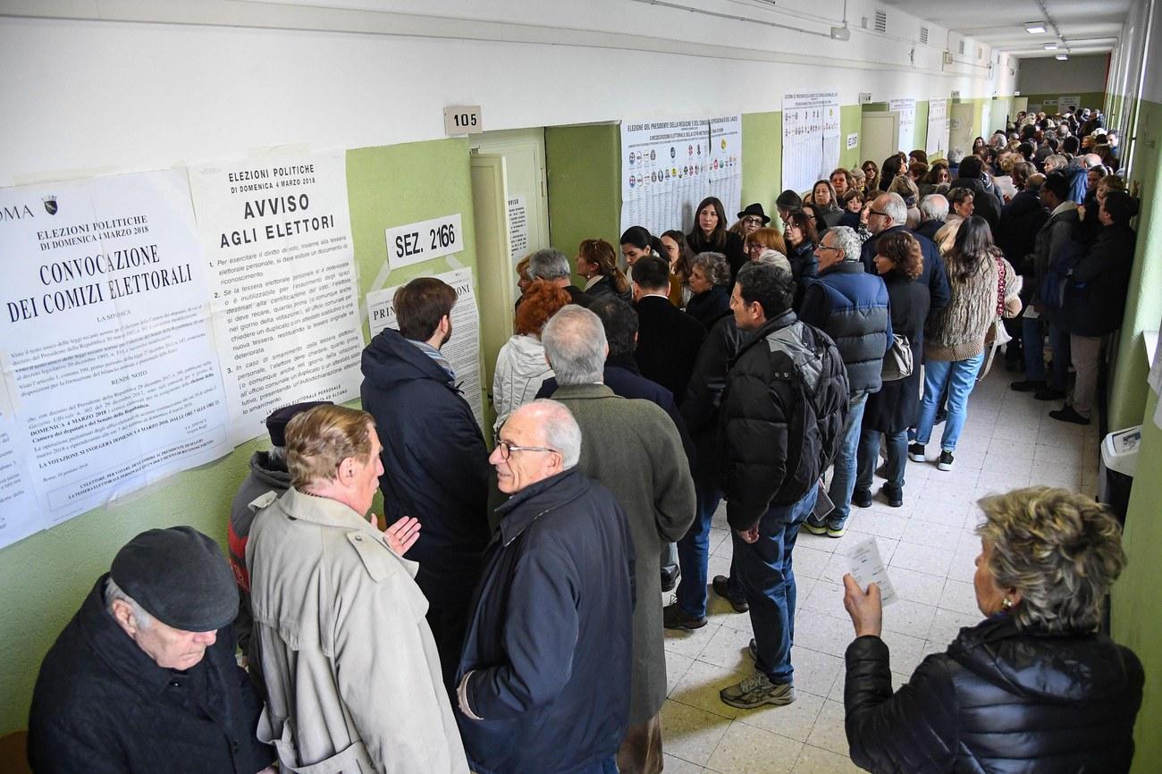 Des électeurs prennent leur mal en patience dans un bureau de vote à Rome. [KEYSTONE - ALESSANDRO DI MEO/EPA]