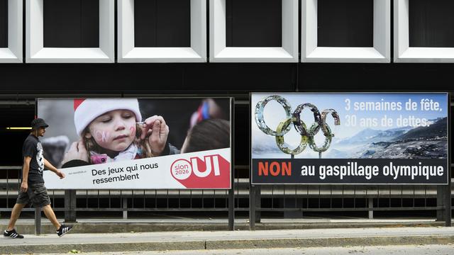 Une affiche des partisans et une des opposants aux JO à Sion en 2026, dans une rue de la ville. [Keystone - Laurent Gilliéron]