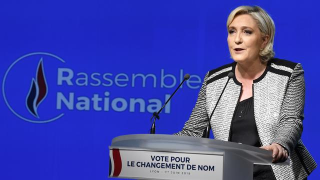 Marine Le Pen devant le nouveau logo de son parti. [AFP - Jean-Philippe Ksiazek]