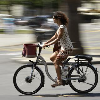 Une cycliste circule à Genève sur un vélo électrique. (image d'illustration) [Keystone - Martial Trezzini]